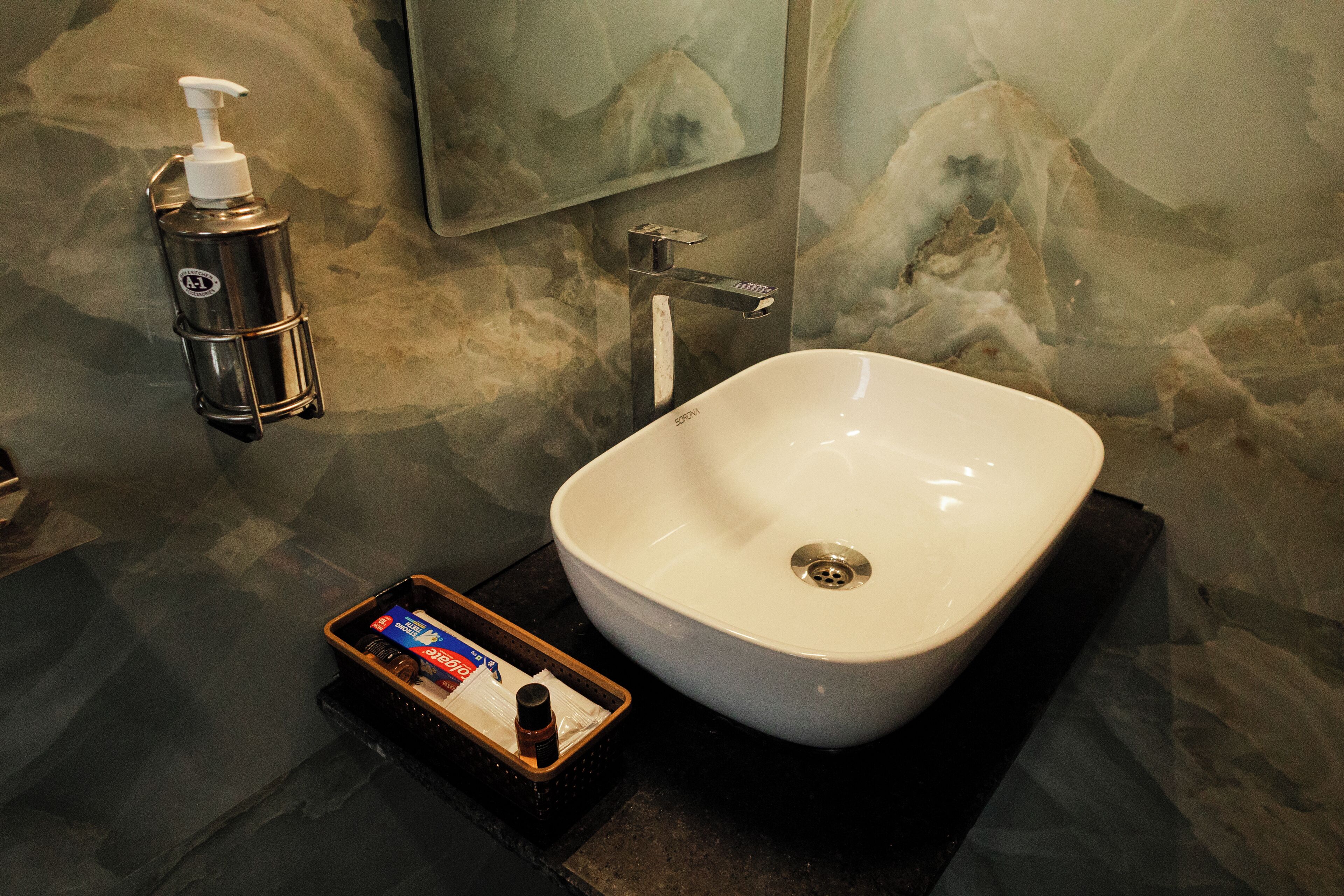 A bathroom with a white sink, a soap dispenser, and a small tray with toiletries.