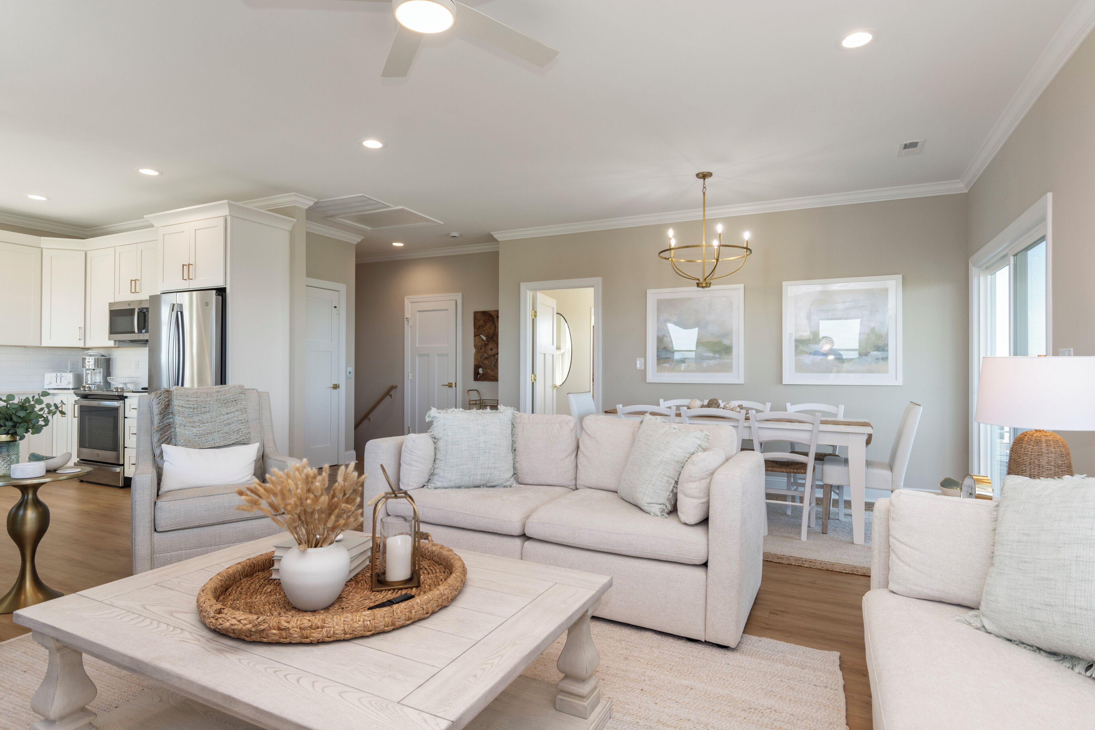 A spacious living room with a neutral color palette, a modern kitchen, and a dining area.