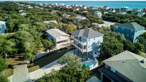 An aerial view of a coastal residential area with houses, a swimming pool, and a clear view of the ocean. - Endless Views | Luxury 4BR Emerald Isle Retreat w/ Pool & Ocean Breezes (Emerald Isle)