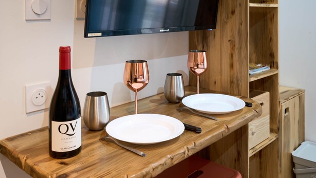 A wooden counter with a bottle of wine, two glasses, and a plate.