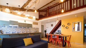 A modern kitchen with blue cabinets, a wooden dining table with red chairs, and a staircase leading to an upper level. - Unique charm - Clim - 6 pers in the heart of Carca (Carcassonne)
