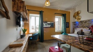 A modern kitchen with a wooden countertop, a dining area with a table and chairs, and a kitchen island with stools. - Comfortable & bright studio - Air conditioning - Centre (Carcassonne)