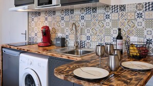A compact kitchen with a washing machine, a coffee maker, a sink, and a tiled backsplash. - Comfortable & bright studio - Air conditioning - Centre (Carcassonne)