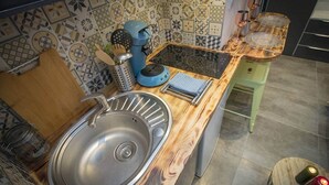 Una cocina con un lavamanos de acero inoxidable, encimera de madera y una cafetera.