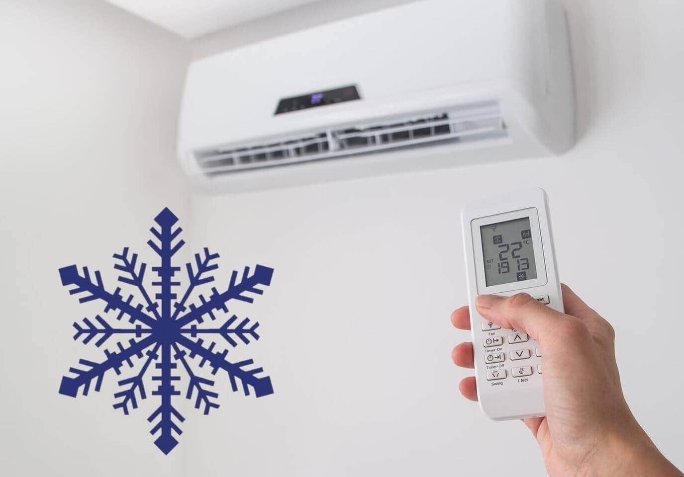 Una mano sosteniendo un termostato digital, con un adorno de copo de nieve en la pared.