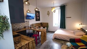 Ein gemütlicher Wohnraum mit Küchenbereich, Esstisch, Bett und Sofa.