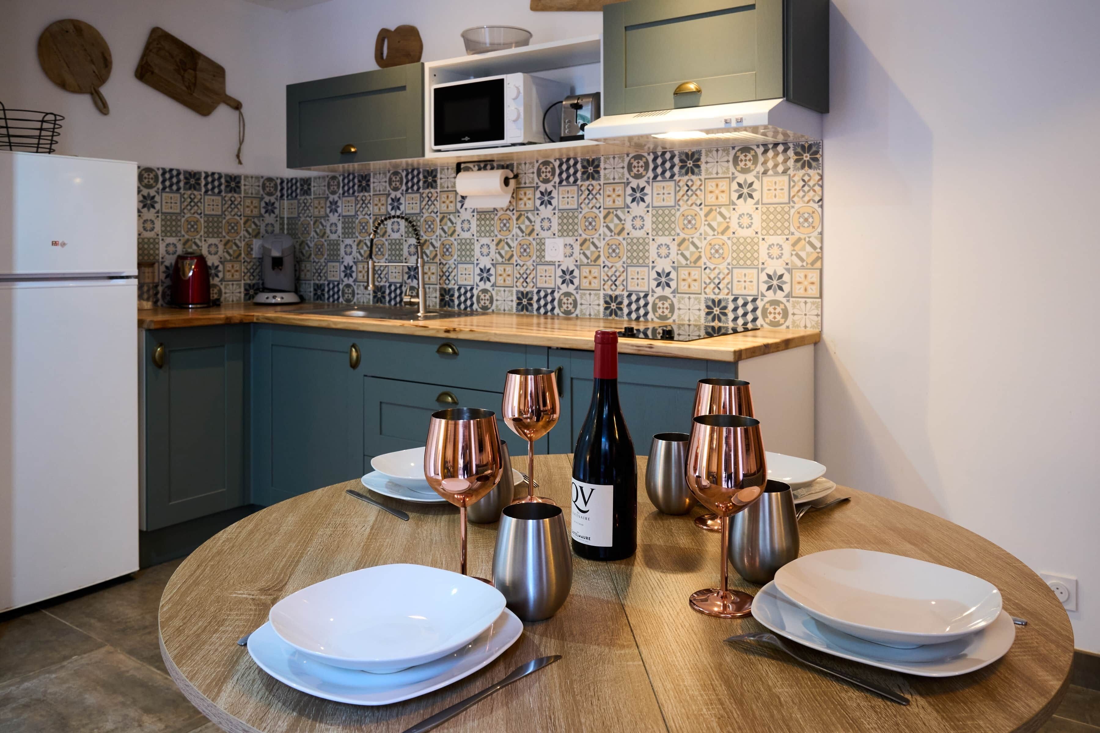 Een keuken met een eettafel gedekt voor vier personen, inclusief wijnglazen en een fles wijn.