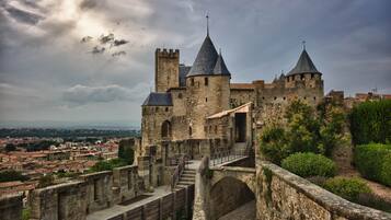 Un castillo de piedra histórico con múltiples torres y una entrada fortificada.