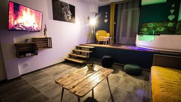 Een moderne woonkamer met een open haard, een trap, een gele fauteuil en een flatscreen-televisie.