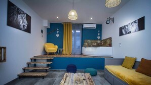 A compact living space with a sofa, a small table, a chair, a bed, and a staircase leading to an upper level. - T2 with jacuzzi and terrace (Carcassonne)