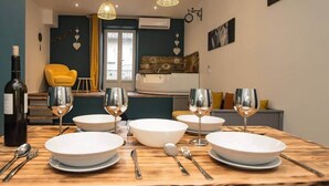 A dining table set with white plates, bowls, and wine glasses, with a bottle of wine and a yellow chair in the background. - T2 with jacuzzi and terrace (Carcassonne)