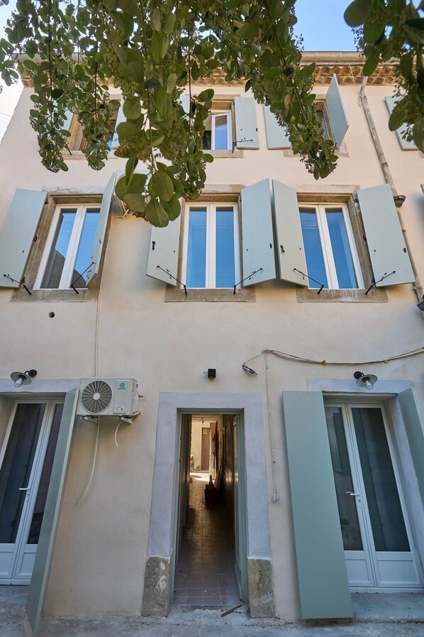 Un immeuble à plusieurs étages doté de fenêtres ouvrantes et d’une porte d’entrée centrale.