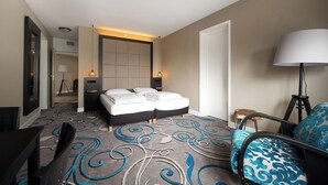 Una habitación de hotel con una cama grande, un escritorio, una silla y una lámpara.