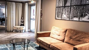 Una sala de estar moderna con un sofá color beige, una alfombra estampada y una mesa de centro de vidrio.