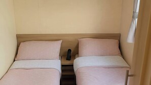 A small, compact bedroom with two single beds, each with a geometric-patterned duvet and pillow. - Golden Gate Holiday Centre - 19059 (Abergele)