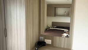 Een slaapkamer met een houten garderobe, een nachtkastje met een stopcontact, en een bed met een bedsprei met een patroon.