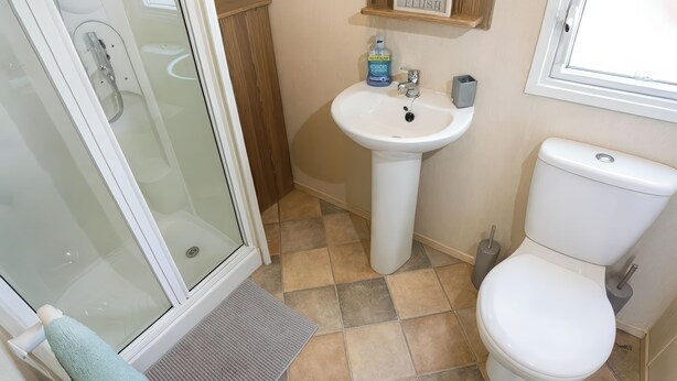 A bathroom with a glass shower enclosure, a white sink, and a toilet. - Marton Mere Holiday Village - 18682 (Blackpool)