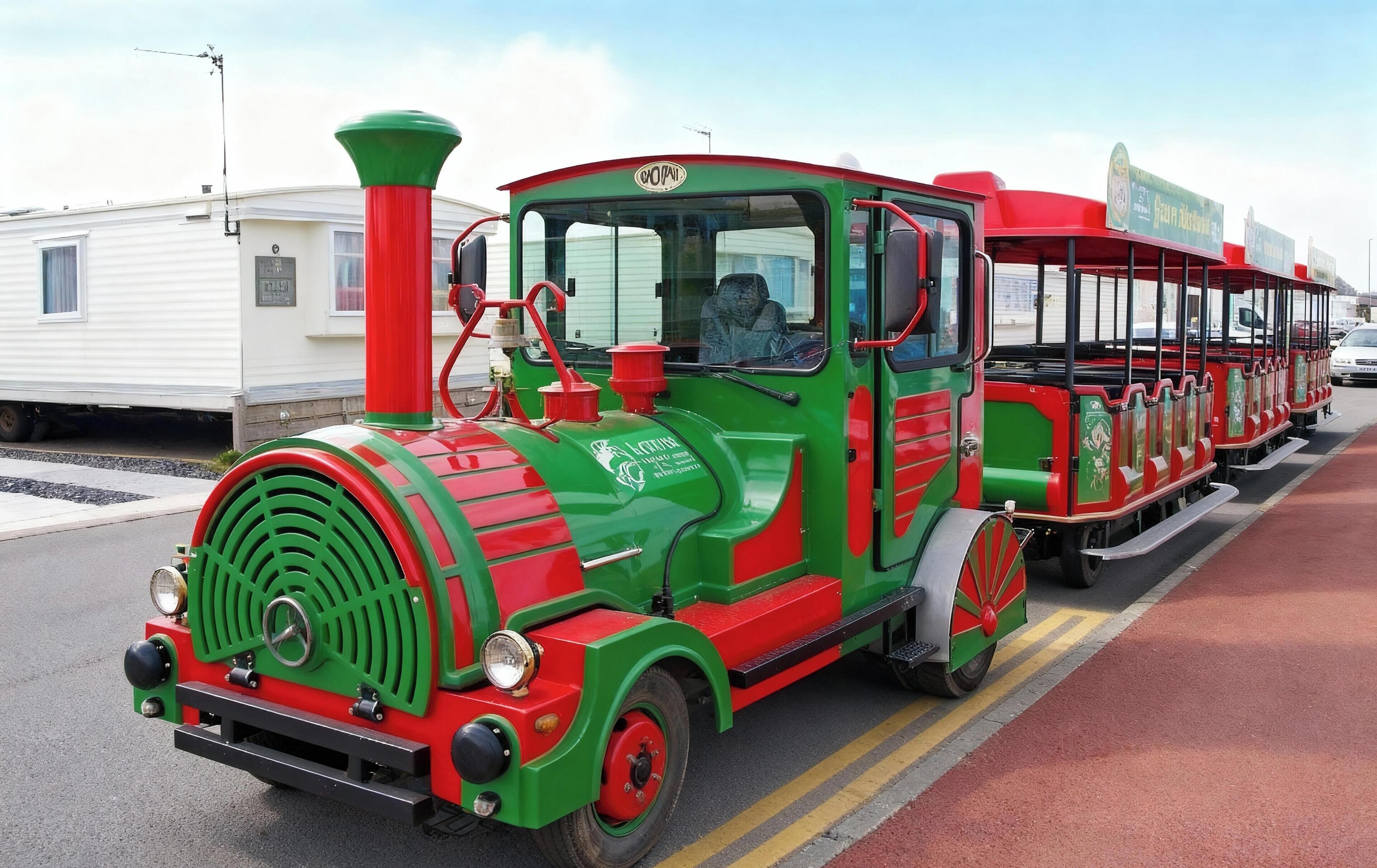 Een trein in groen en rood met een machinistcabine, rijdend over een rails.