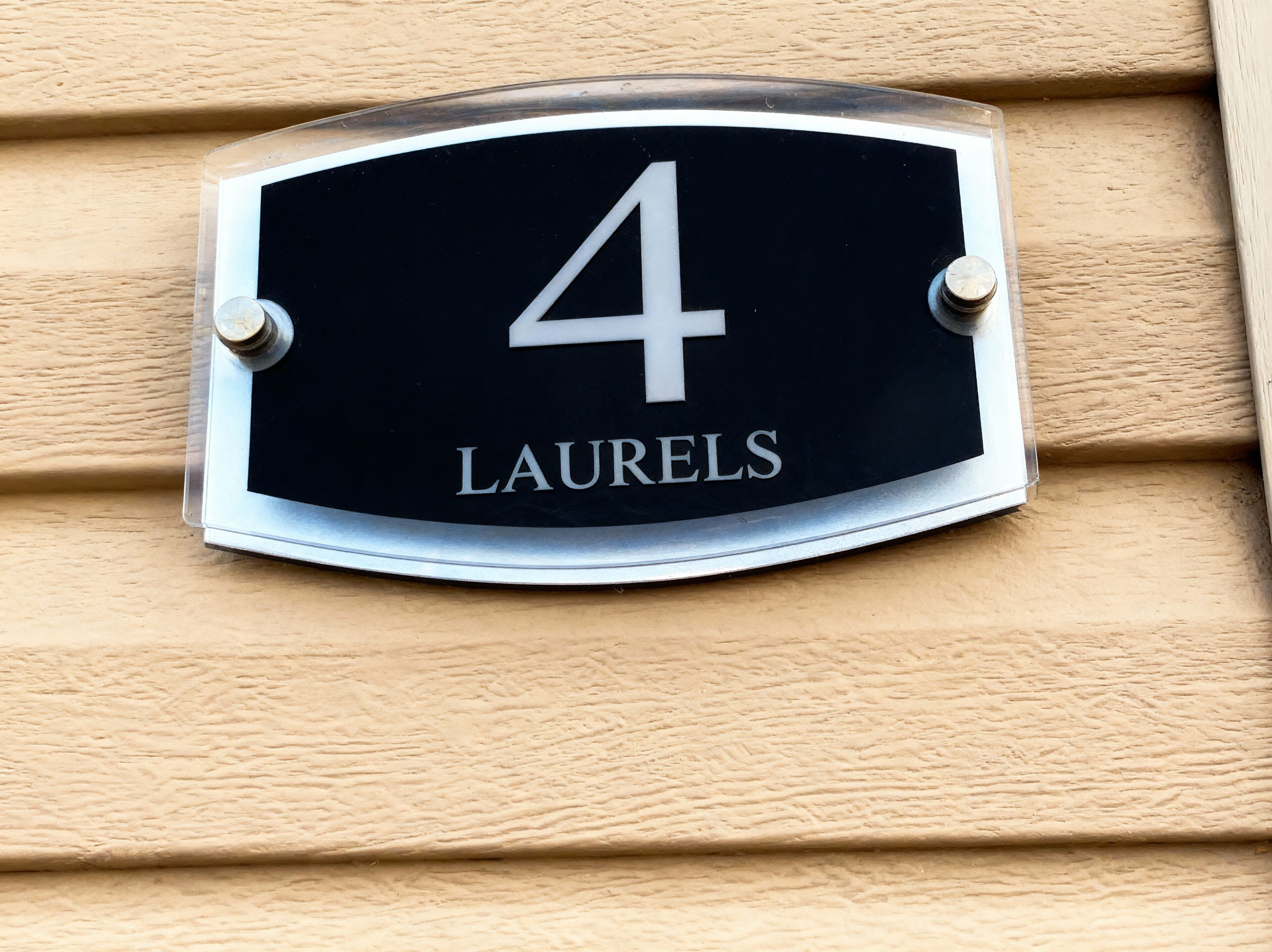 A house number plaque with the number 4 and the name "LAURELS" on a beige wall.