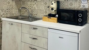 Une cuisine compacte avec des meubles de couleur claire, un four à micro-ondes encastré et une machine à café.