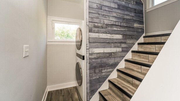 A modern staircase with wooden steps and a dark wood panel wall.