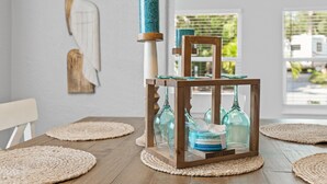 Ein Esstisch mit gewebten Platzsets, einem Glas-Kerzenhalter und einem Holzstuhl.
