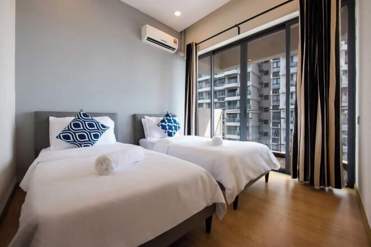 Une chambre d’hôtel avec deux lits, une grande fenêtre et un appareil de climatisation.