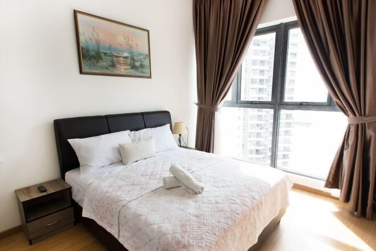 A hotel room with a bed, a nightstand, a painting on the wall, and a window with curtains.