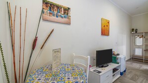 Ein Zimmer mit einem Bett, einem Fernseher, einem kleinen Tisch und einem Bild an der Wand.