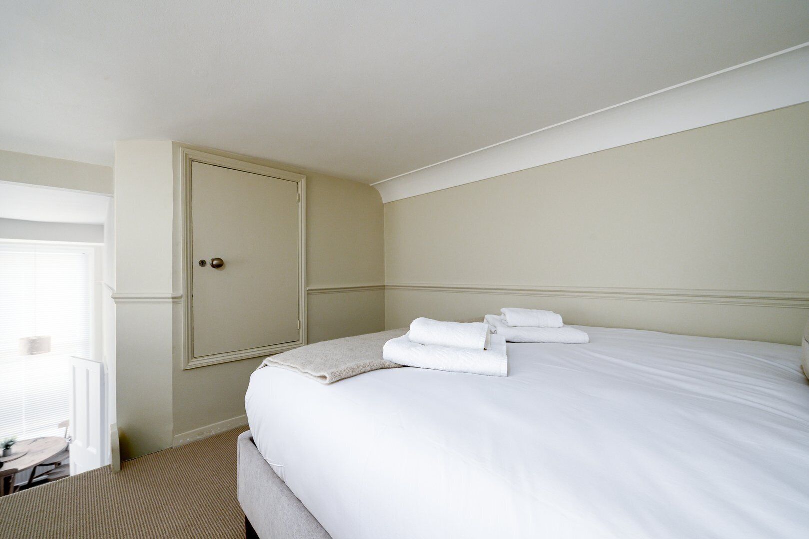 Ein Hotelzimmer mit einem großen Bett, einer Tür und einem kleinen Tisch mit Stühlen.