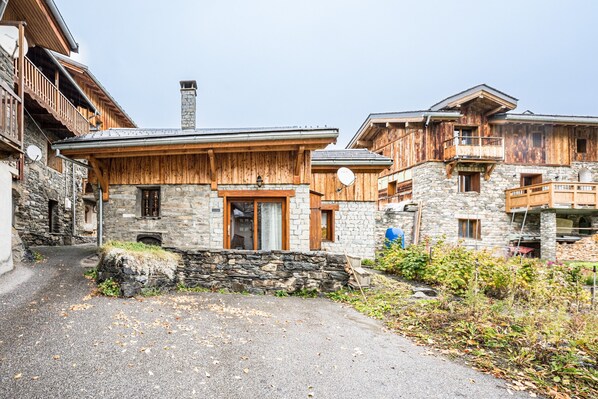 A rustic mountain lodge with stone walls, wooden balconies, and a stone chimney.