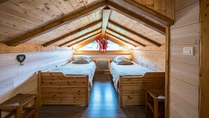 Eine Holzhütte mit zwei Betten, einer geneigten Decke und einem Fenster mit Blick.