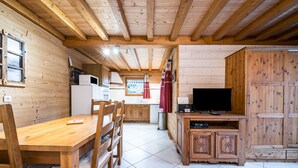 Ein Holzinterieur mit Esstisch, Stühlen, einem Fernseher und Schränken.
