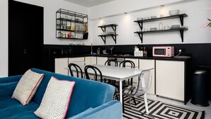 A modern kitchen with black and white cabinetry, a dining table with chairs, and a blue sofa with patterned pillows.