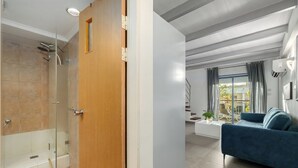 A modern bathroom with a glass shower enclosure and a wooden door.