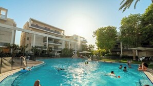 A swimming pool surrounded by buildings, with people swimming and relaxing.