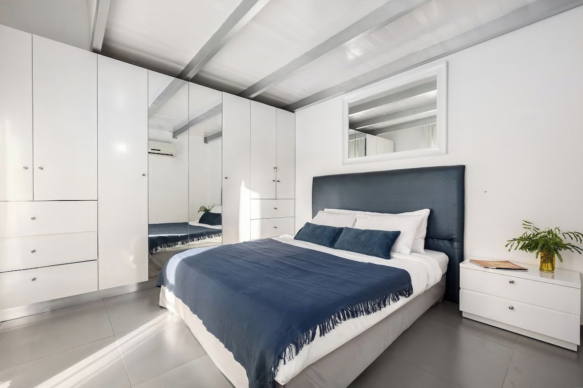 Un dormitorio moderno con una cama grande, armario empotrado y mesita de noche con una planta.