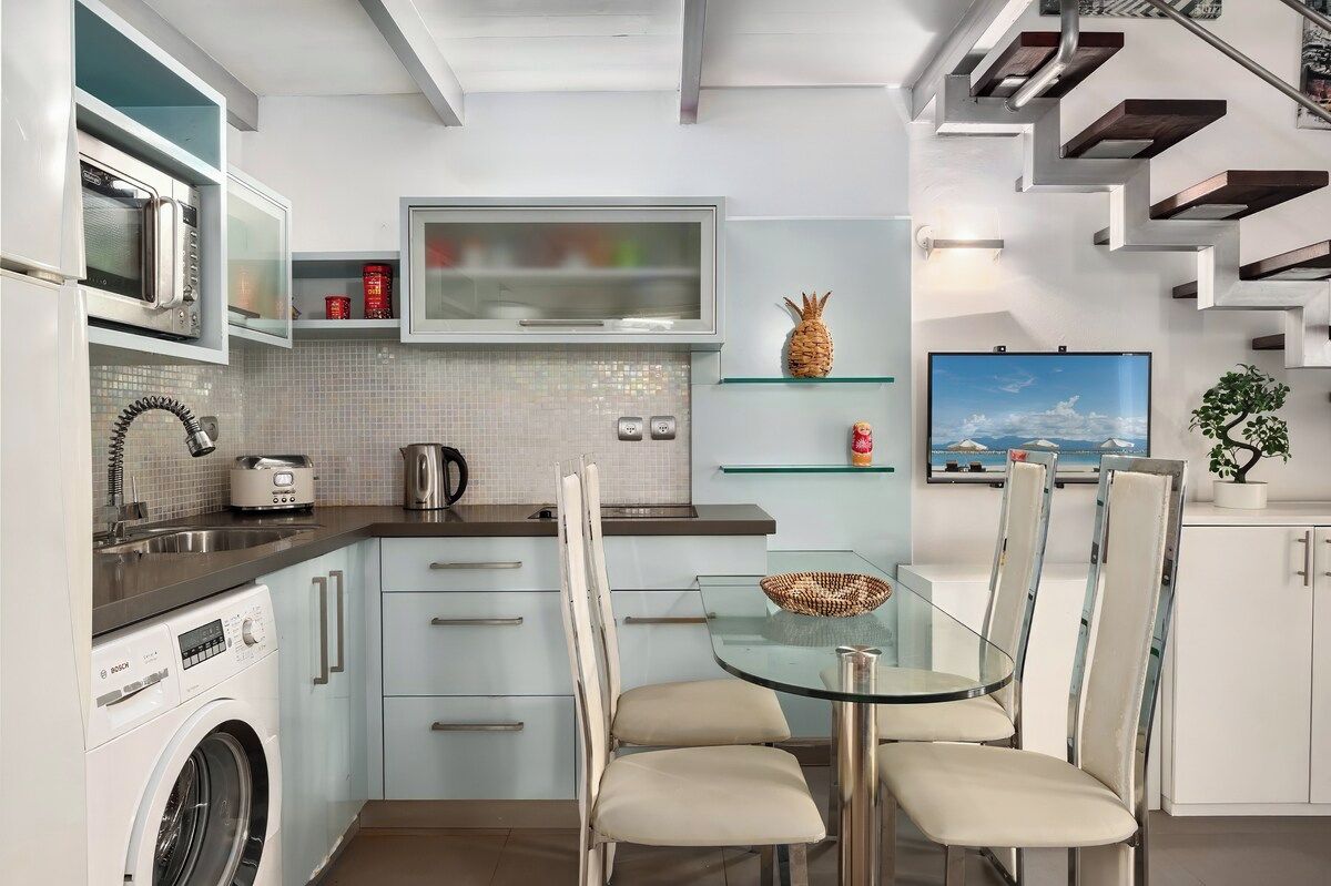 A modern kitchen with built-in appliances, a glass dining table, and a view of the outdoors.