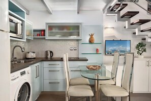 A modern kitchen with built-in appliances, a glass dining table, and a view of the outdoors.