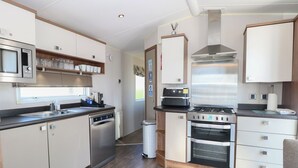 Eine kleine Küche mit Mikrowelle, Herd, Backofen und Spüle.