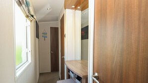 Ein schmaler Flur mit einer Holztür, einer Bank und einem Fenster.