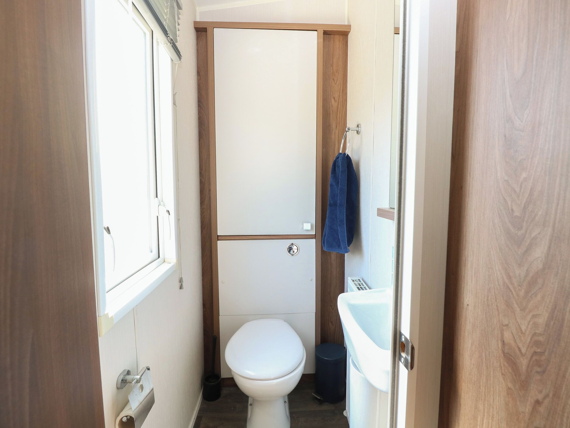 Un bagno compatto con il water, un lavandino e un asciugamano appeso al muro.