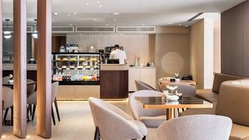 Ein modernes Café mit Barbereich, Sitzgelegenheiten und einer Theke mit einer Kaffeemaschine.