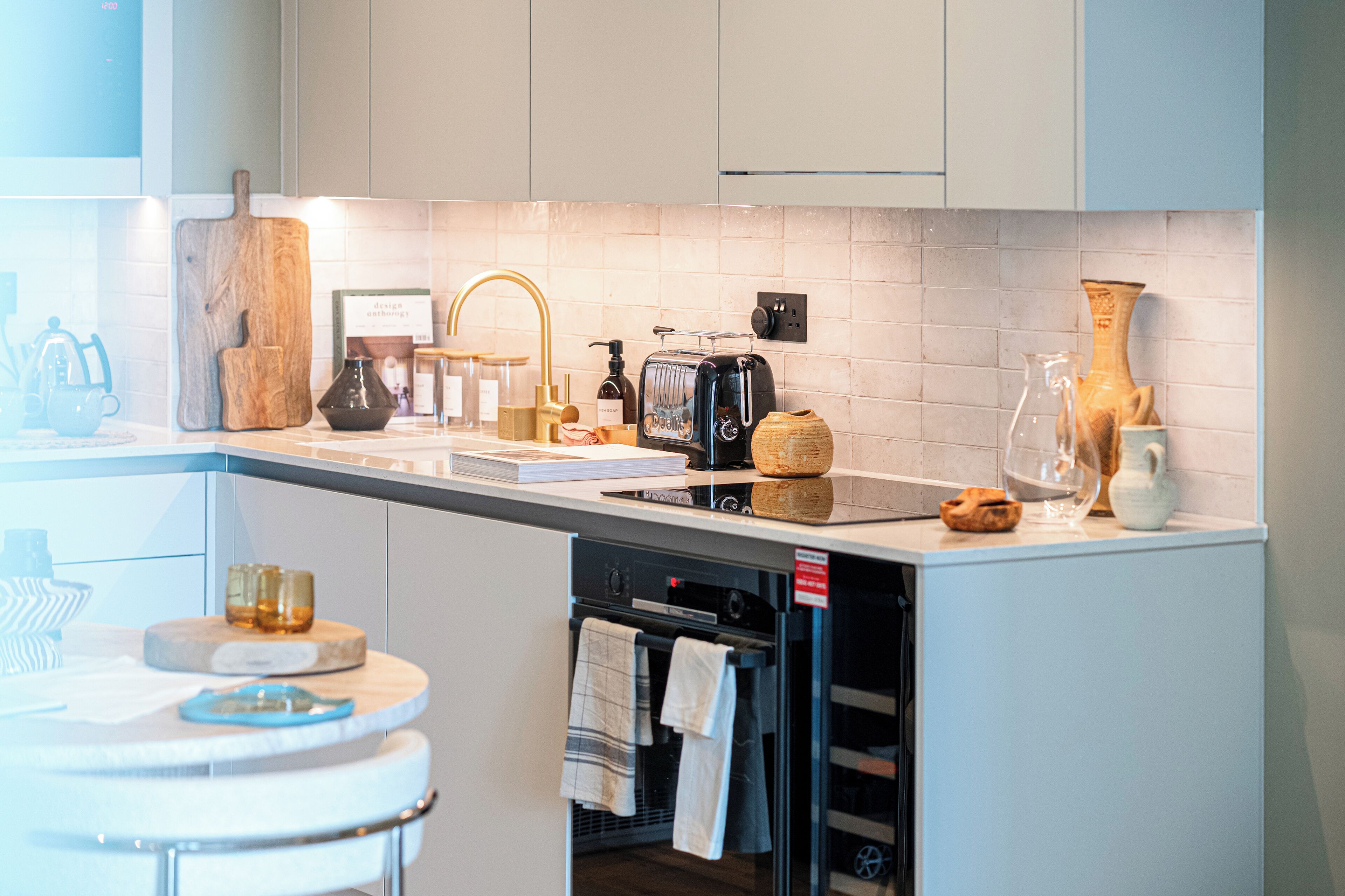 A modern kitchen with a white countertop, a built-in oven, and various kitchen appliances.