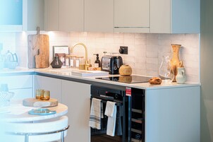 Una cocina moderna con encimera blanca, horno empotrado y diversos electrodomésticos.