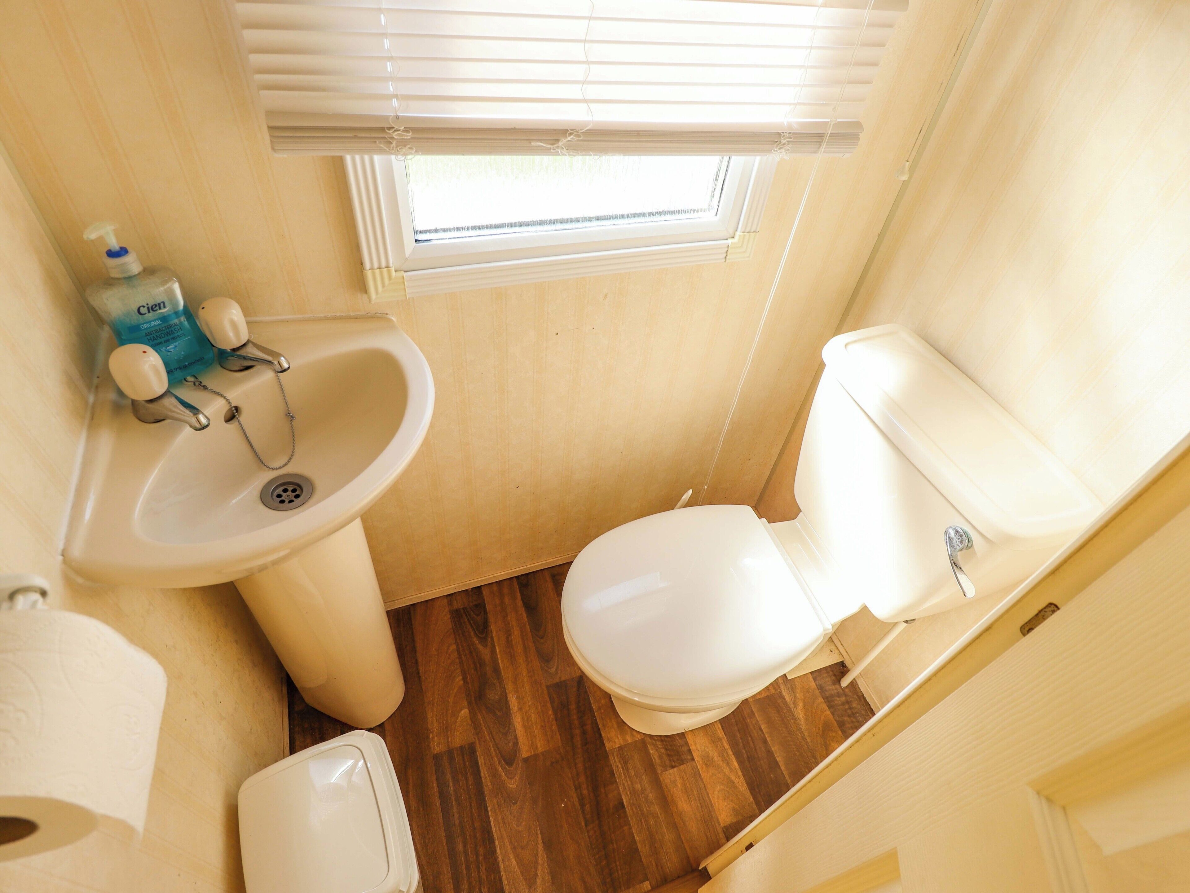 Une petite salle de bain comprenant un lavabo, des toilettes et une fenêtre.