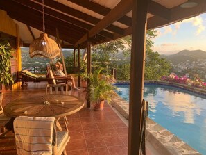 Un espacio al aire libre cubierto con piscina, sillas de descanso y una silla colgante.
