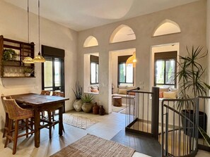 A spacious living area with a wooden dining table, comfortable seating, and a staircase leading to an upper level. - Artisan Duplex • Talpiot Market by SeaNRent (Tiberias)
