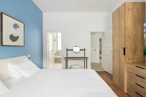 A bedroom with a bed, a bedside table, a mirror, and a wooden wardrobe.