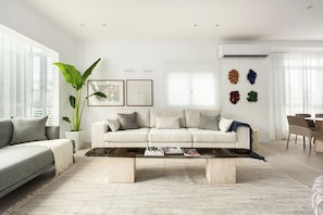 A modern living room with a sofa, coffee table, and a large plant.